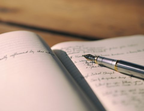 摊开的纸质笔记本上画着柱状图与手写批注旁边放着一支笔